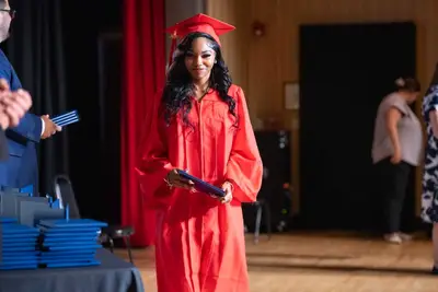 Qalin jabiyay koofiyad cas iyo gown ayaa dhoola cadeynaya, isagoo masraxa ku sita shahaado.